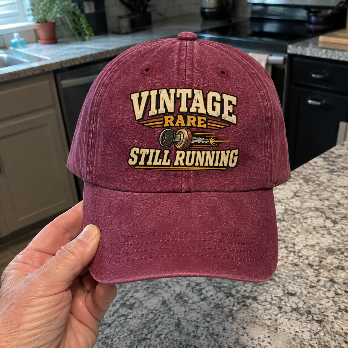 Burgundy vintage washed cap with printed Vintage Rare Still Running slogan, handheld view