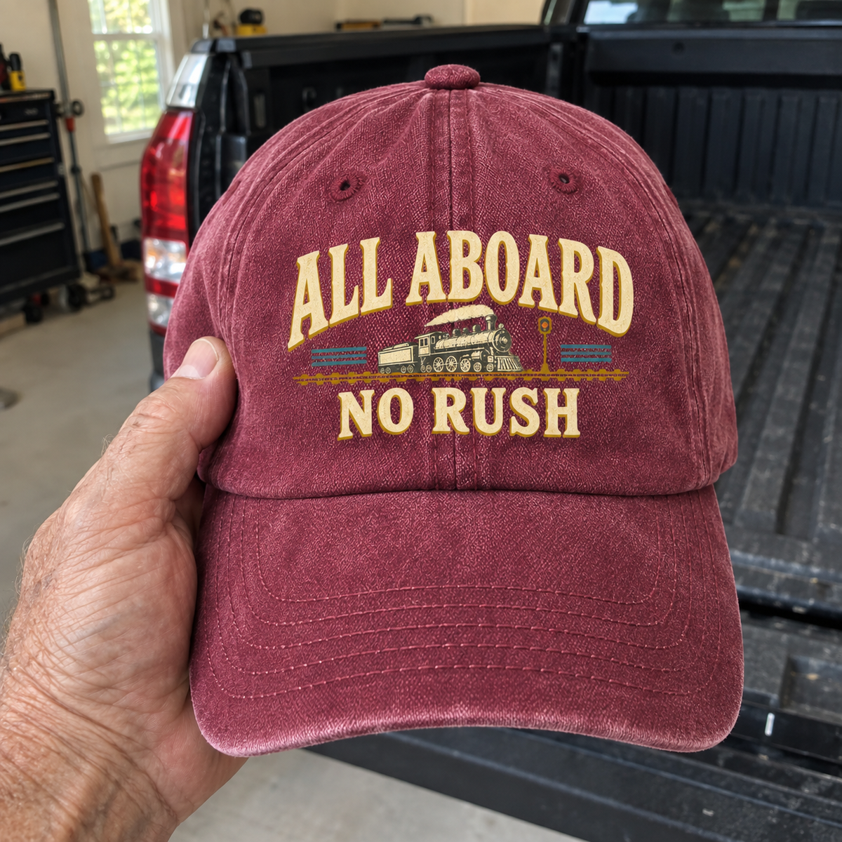 Hand holding vintage washed cap with All Aboard. No Rush printed design