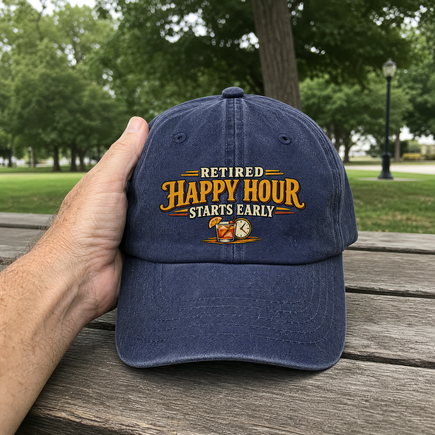 Navy vintage washed cap with printed “Retired Happy Hour Starts Early” slogan, handheld outdoor view