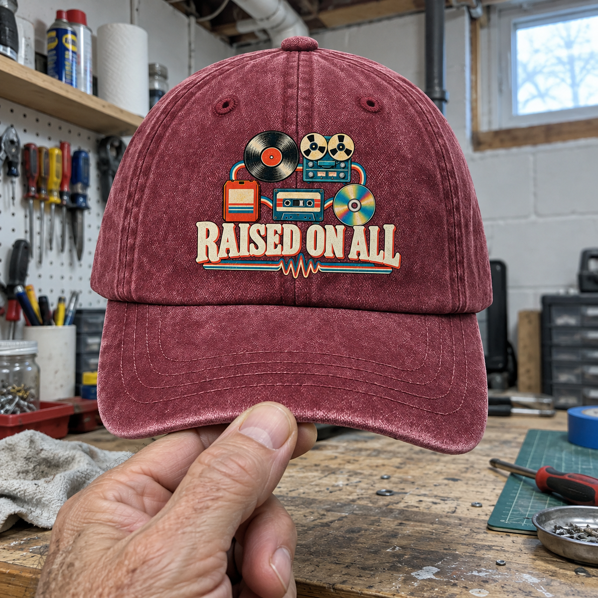 Handheld burgundy vintage washed cap with printed retro music graphics and Raised On All