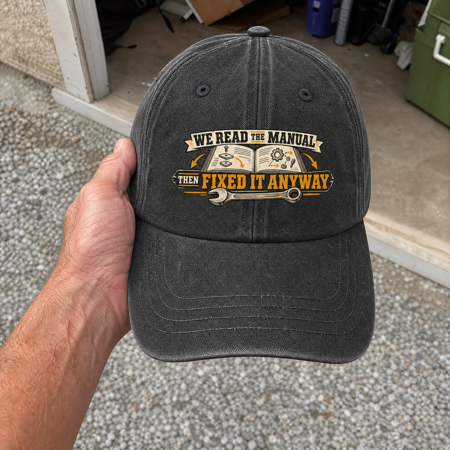Vintage washed cap with printed “We Read the Manual Then Fixed It Anyway” design, handheld