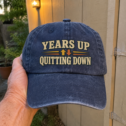 Blue vintage washed cap with printed Years Up Quitting Down slogan held by hand