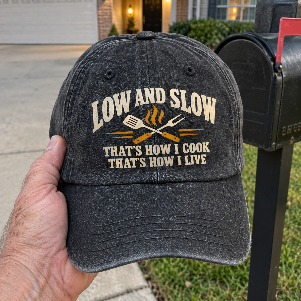 Black vintage washed cap with printed Low And Slow cooking slogan, front handheld view