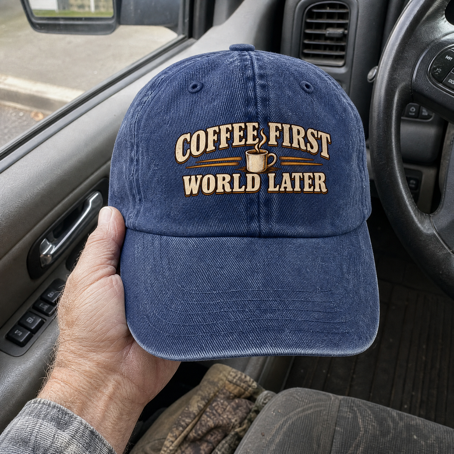 Blue vintage washed cap with printed Coffee First. World Later slogan, handheld view