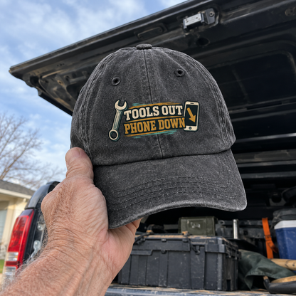 Dark gray vintage washed cap with printed Tools Out. Phone Down slogan, handheld outdoors