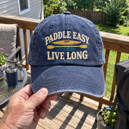 Blue vintage washed cap printed with Paddle Easy Live Long slogan, kayak design, handheld outdoors