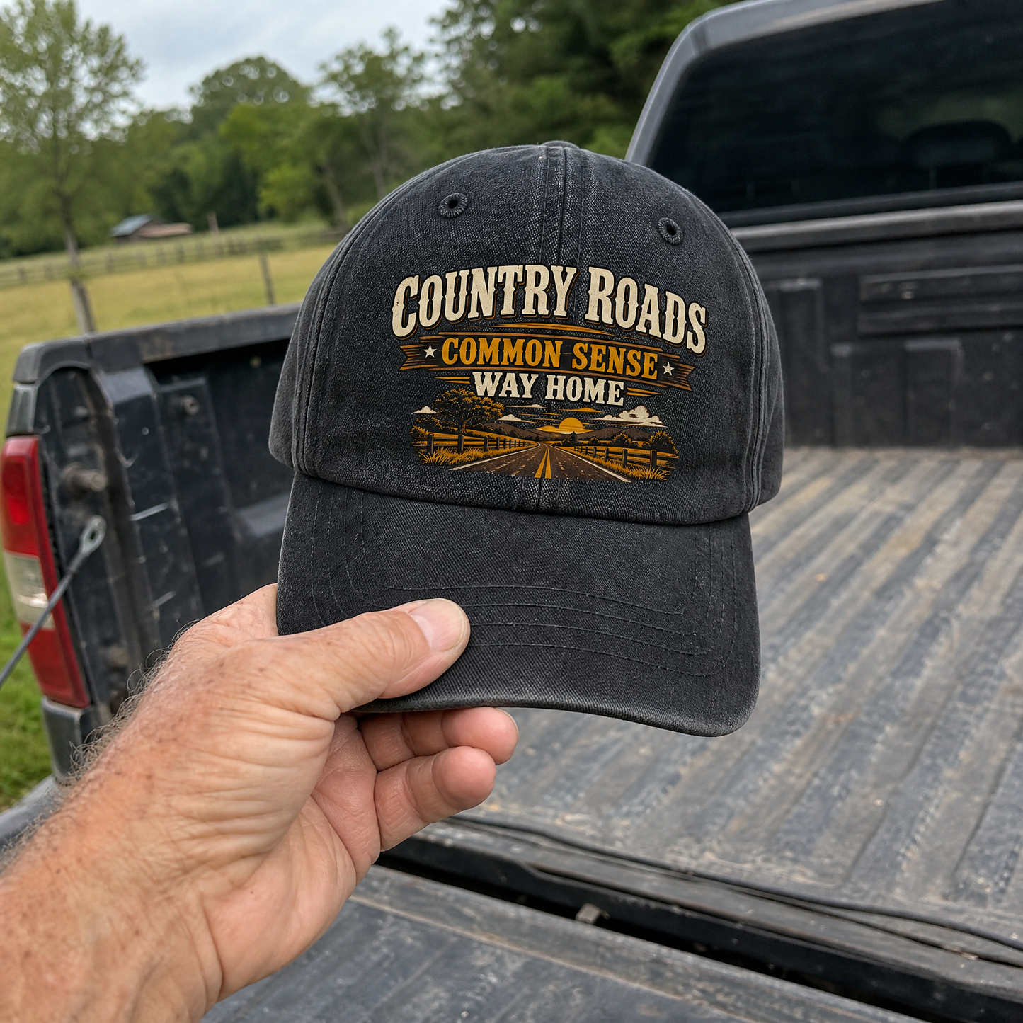 Hand holding vintage washed cap with Country Roads. Common Sense Way Home printed design
