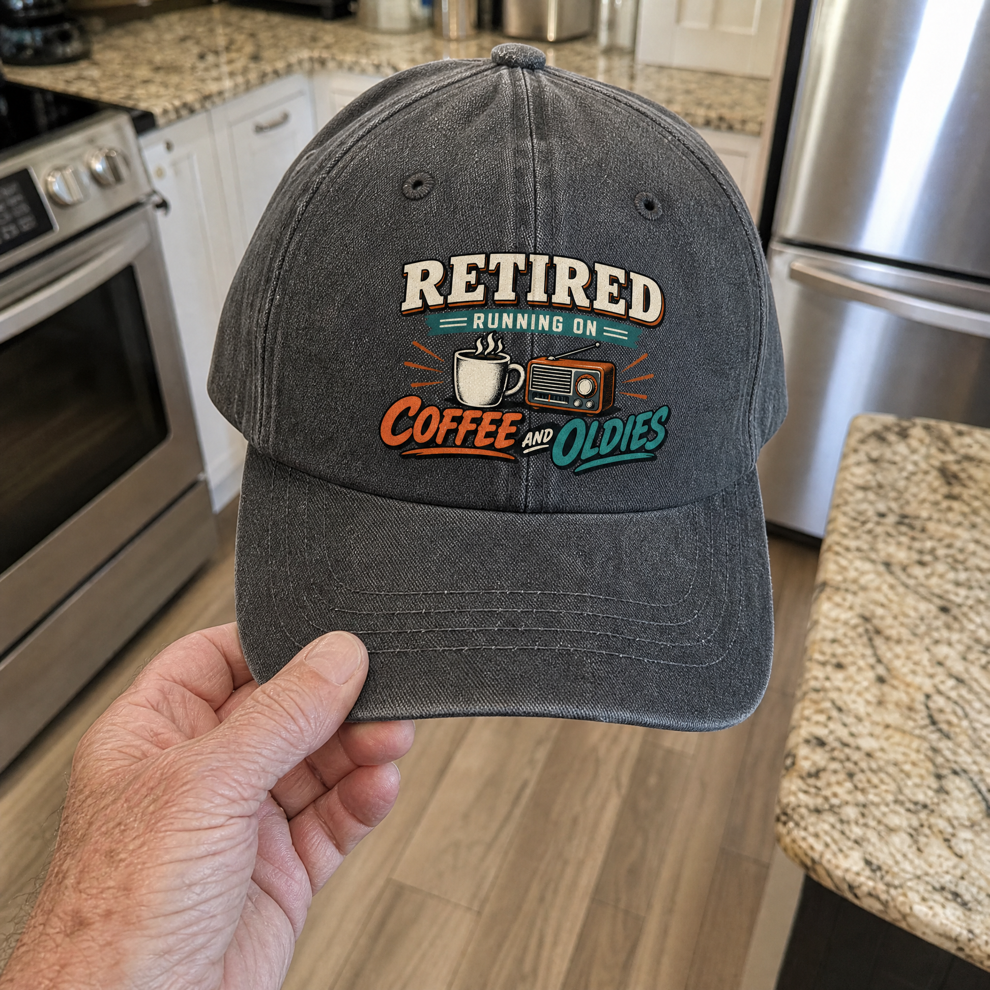 Dark gray vintage washed cap with printed Retired Running On Coffee And Oldies slogan, handheld.