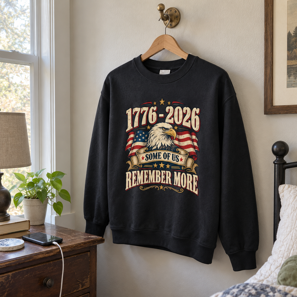 Black vintage sweatshirt hanging with printed 1776-2026, eagle, flag, and Some Of Us Remember More