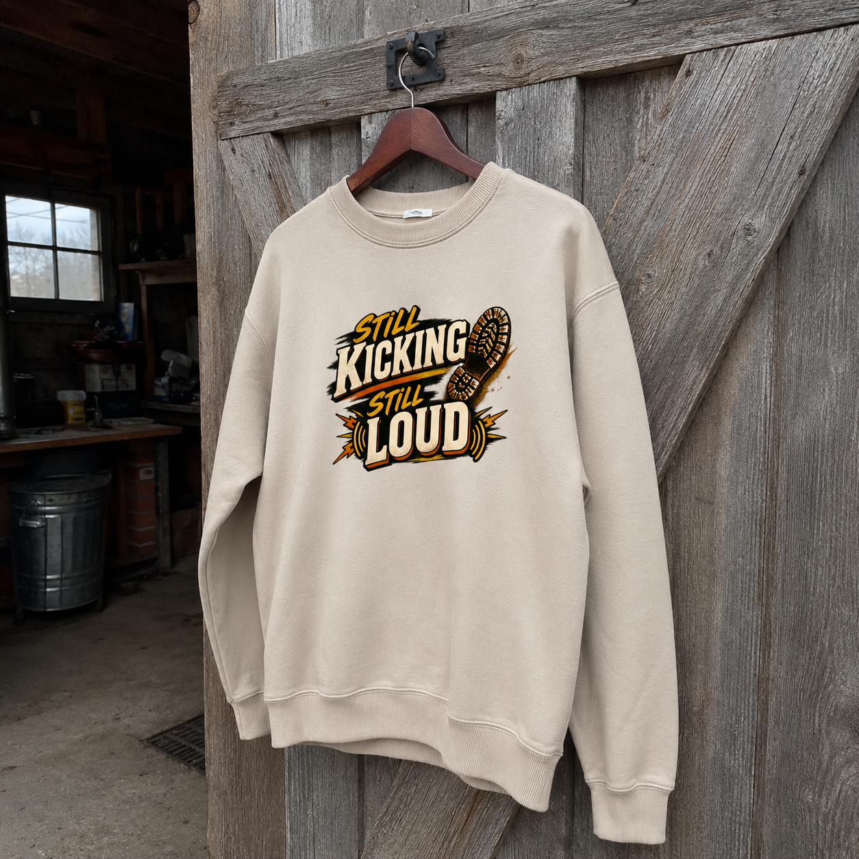 Cream vintage sweatshirt hanging with printed Still Kicking Still Loud slogan design