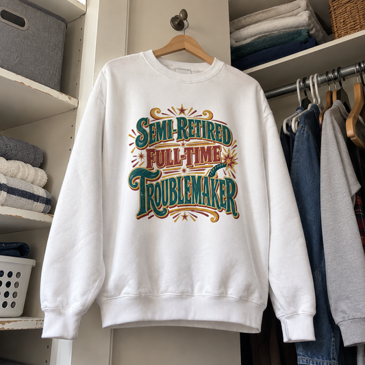 White vintage sweatshirt hanging in closet with colorful Semi-Retired Full-Time Troublemaker print