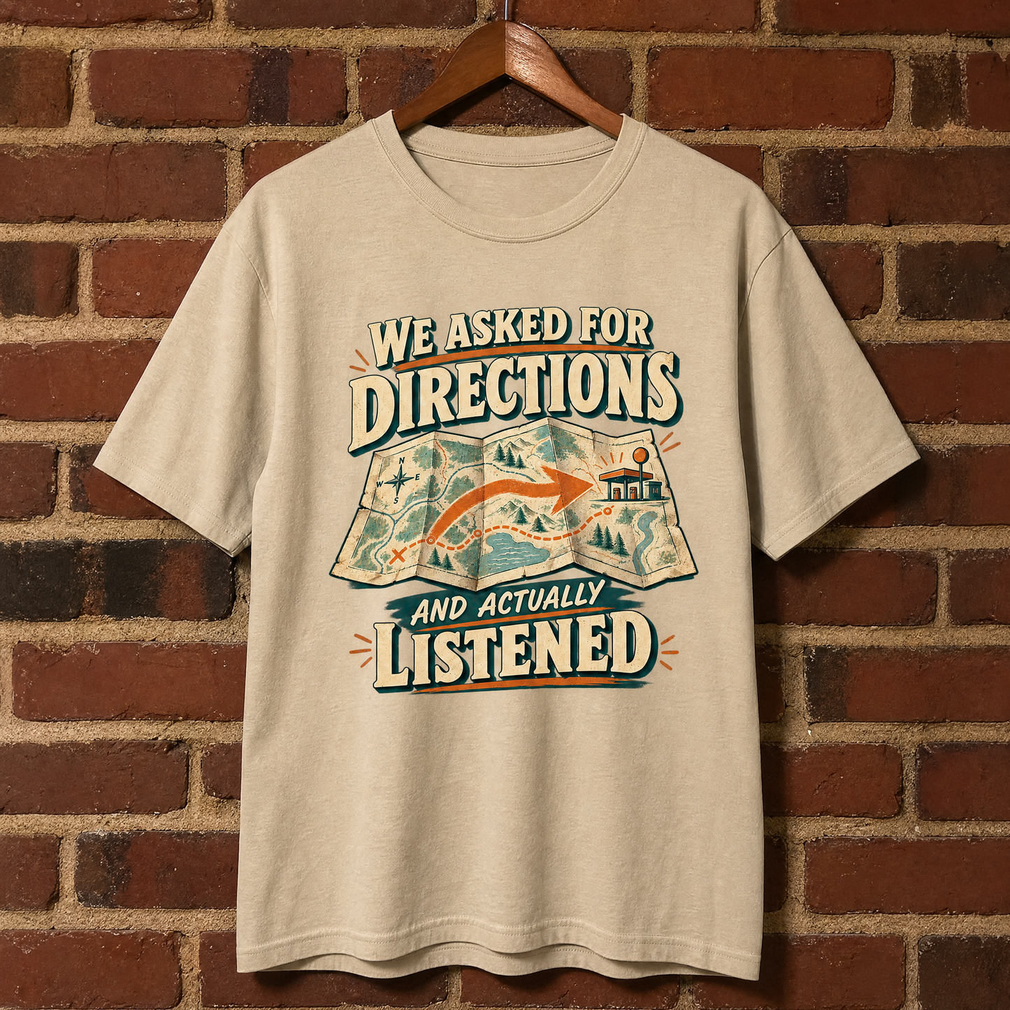 Cream vintage t-shirt hanging against brick wall with “We Asked For Directions And Actually Listened” print