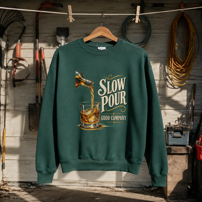 Dark green vintage sweatshirt hanging with printed whiskey pour graphic and Slow Pour Good Company