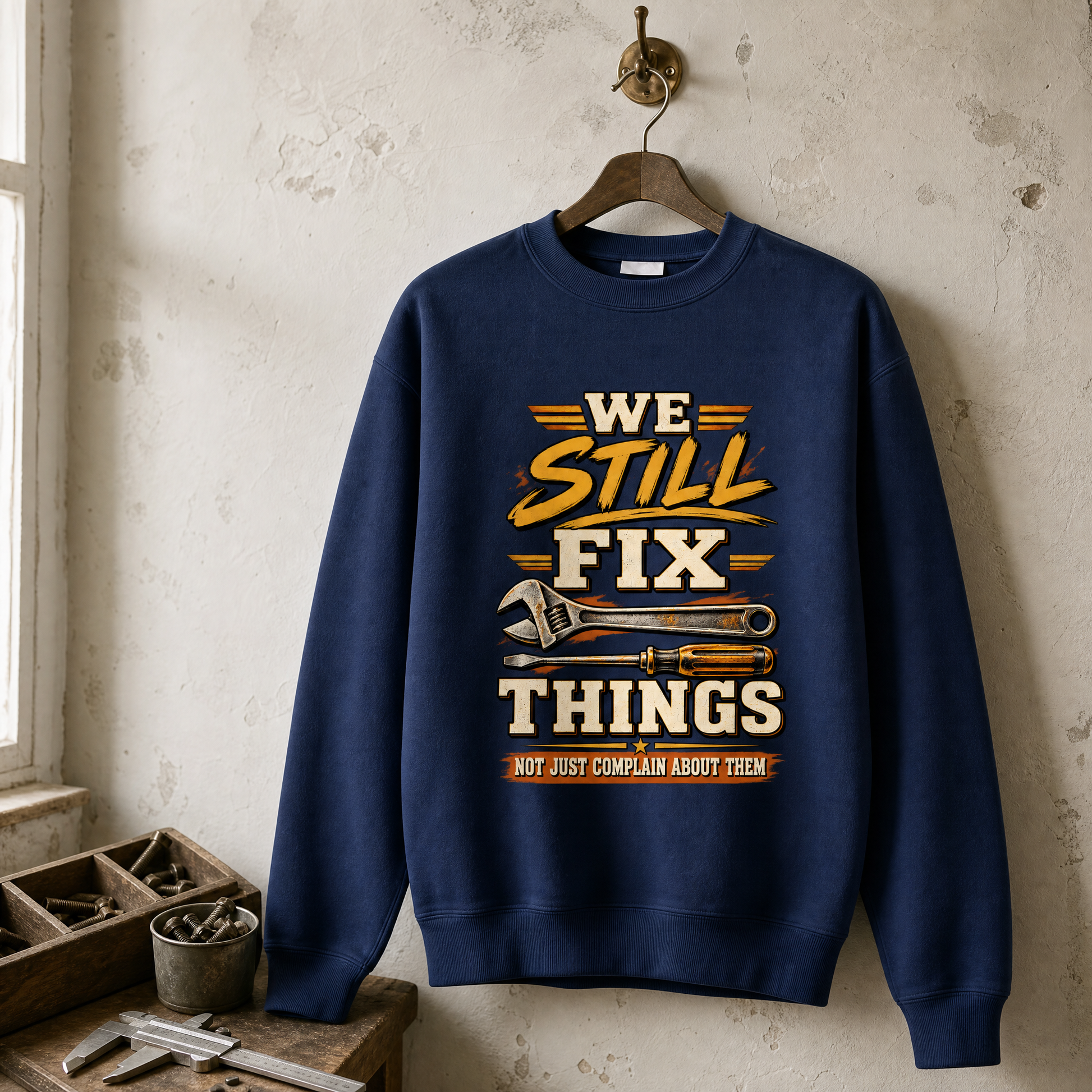 Navy vintage sweatshirt hanging with printed We Still Fix Things slogan and tools design