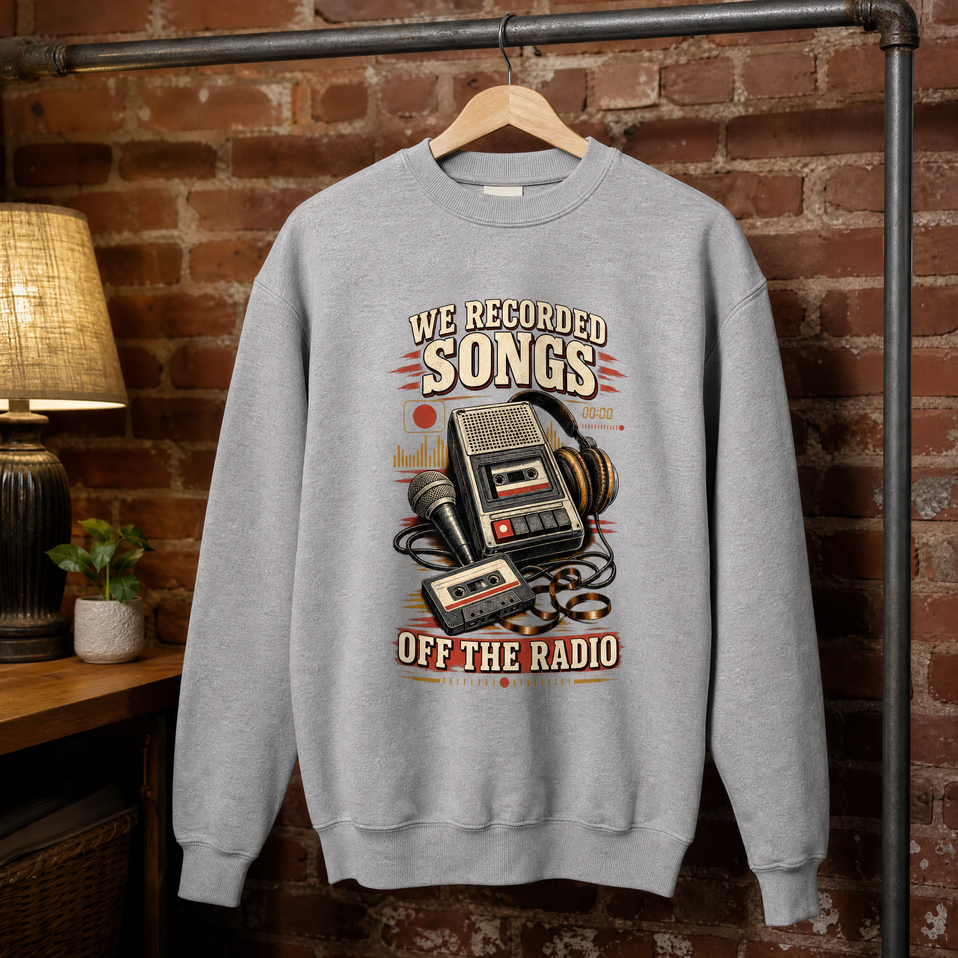 Gray vintage sweatshirt hanging with printed “We Recorded Songs Off The Radio” design featuring radio and cassette.