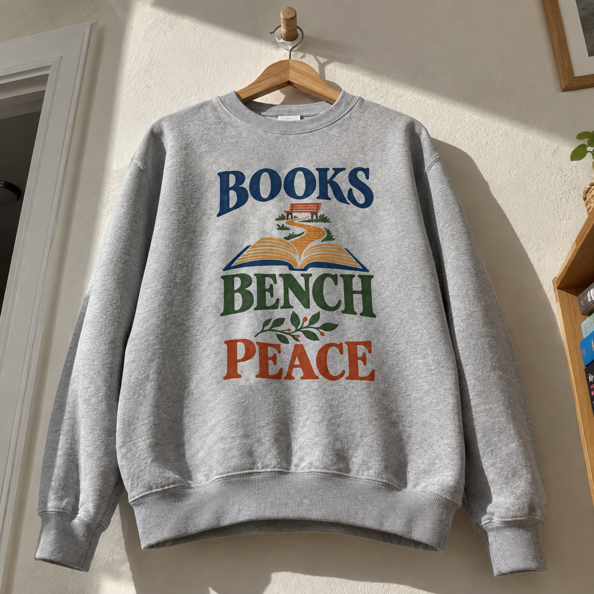 Gray vintage sweatshirt hanging with printed Books Bench Peace design and open book illustration
