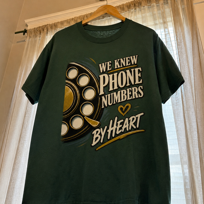 Dark green vintage t-shirt with printed We Knew Phone Numbers By Heart slogan, hanging.