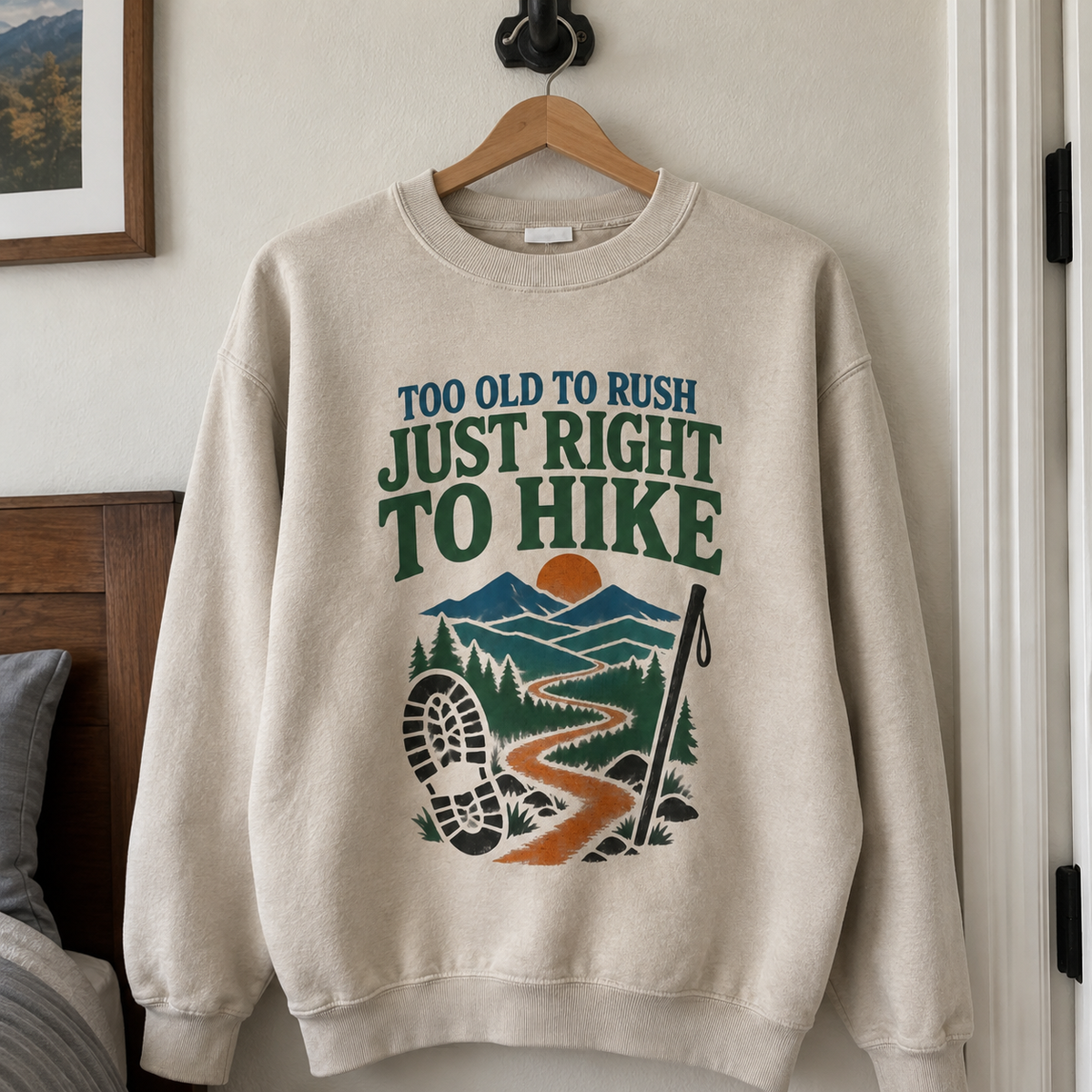 Cream vintage sweatshirt with printed hiking design and slogan, hanging front view on wooden hanger