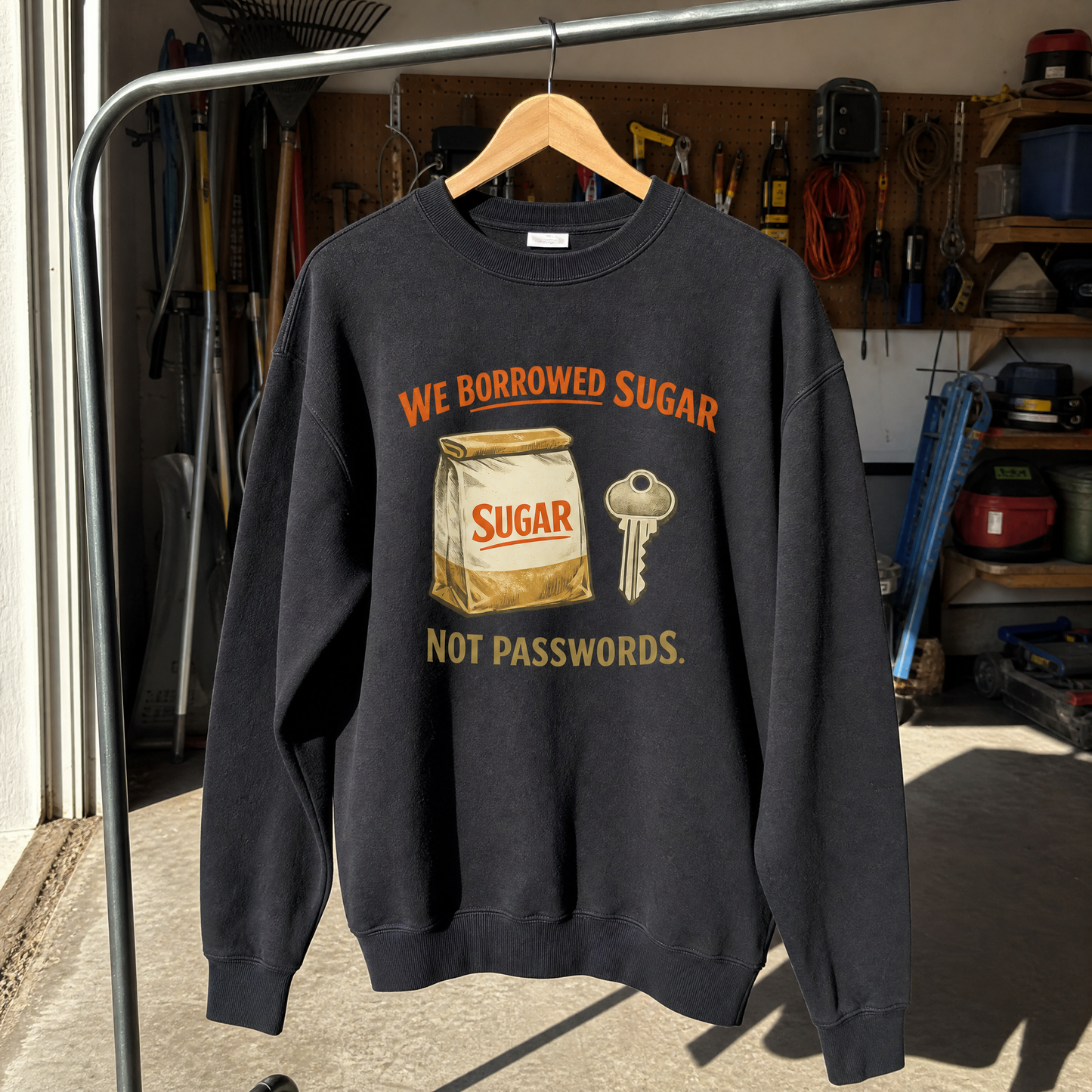 Black vintage sweatshirt hanging with printed sugar bag, key, and “We Borrowed Sugar” slogan