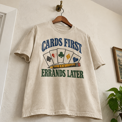 Cream vintage t-shirt hanging, printed with Cards First. Errands Later and playing card graphics