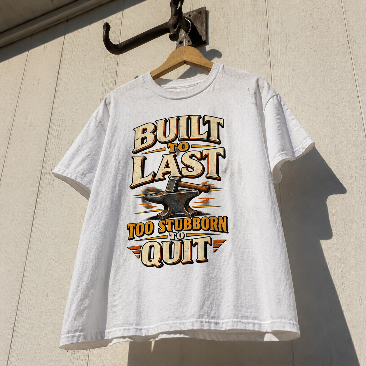 White vintage t-shirt hanging with printed Built To Last Too Stubborn To Quit slogan