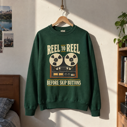 Green vintage sweatshirt hanging with printed reel-to-reel design and “Before Skip Buttons” slogan
