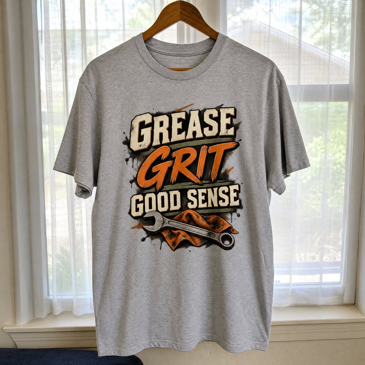 Grey vintage t-shirt hanging with printed Grease Grit Good Sense slogan design