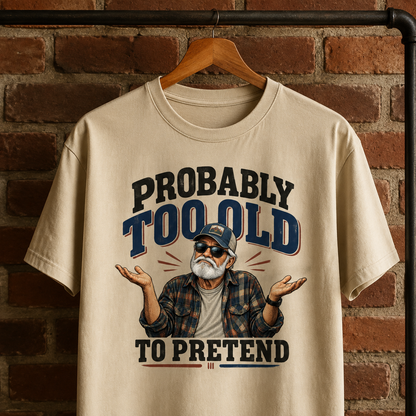 Beige vintage t-shirt hanging with printed “Probably Too Old To Pretend” design and senior man illustration