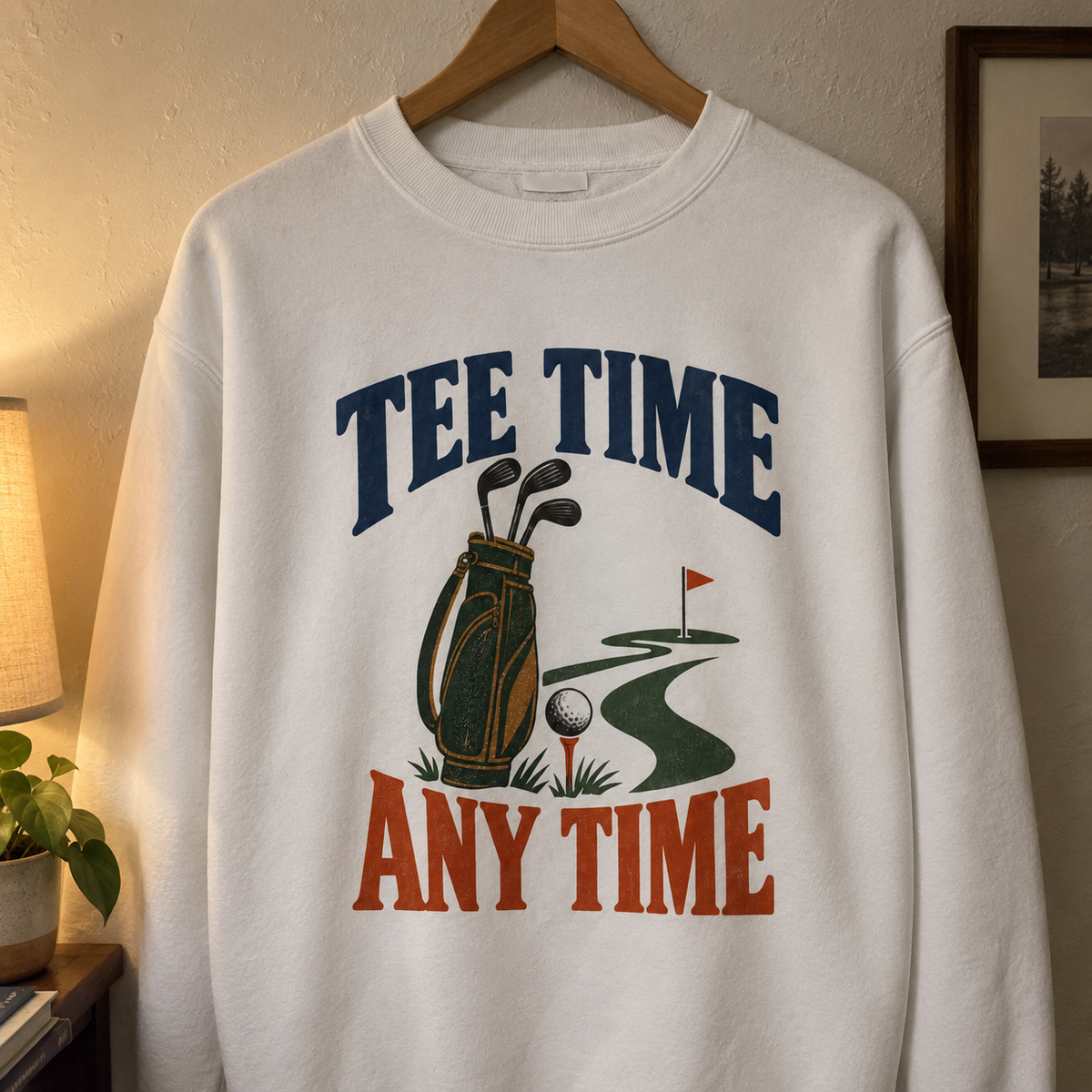 White vintage sweatshirt hanging with printed Tee Time Any Time golf bag and course design