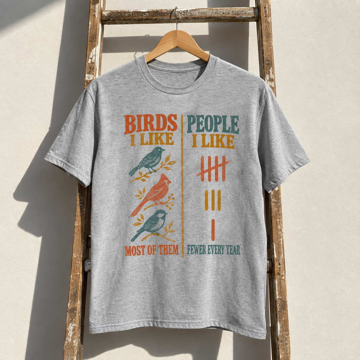 Gray vintage t-shirt hanging with printed bird designs and humorous people tally slogan