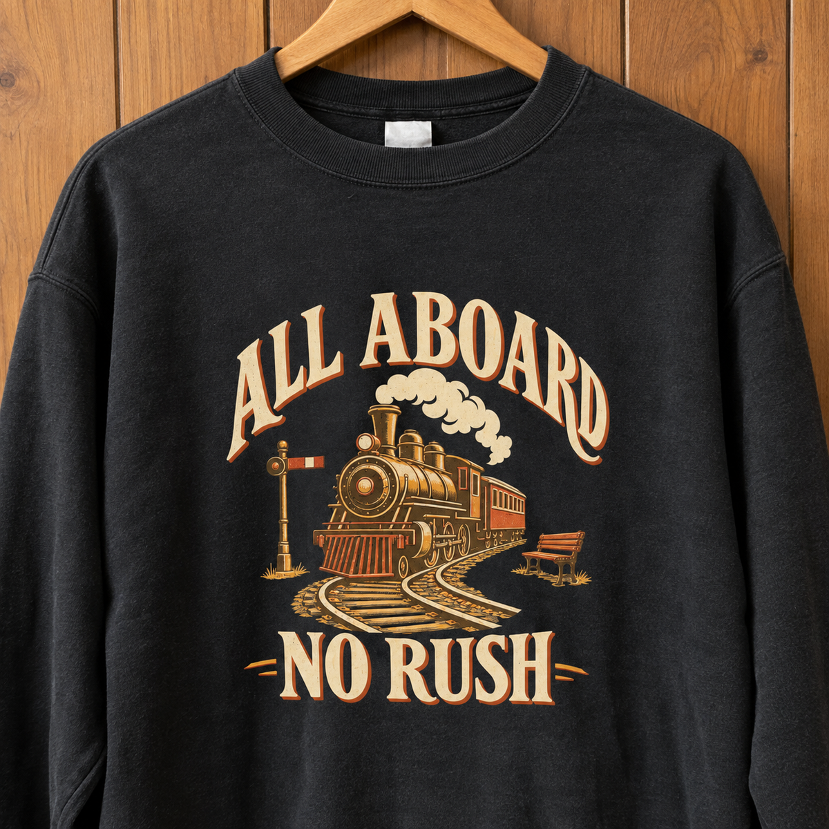 Black vintage sweatshirt hanging on wooden hanger, printed All Aboard No Rush train design