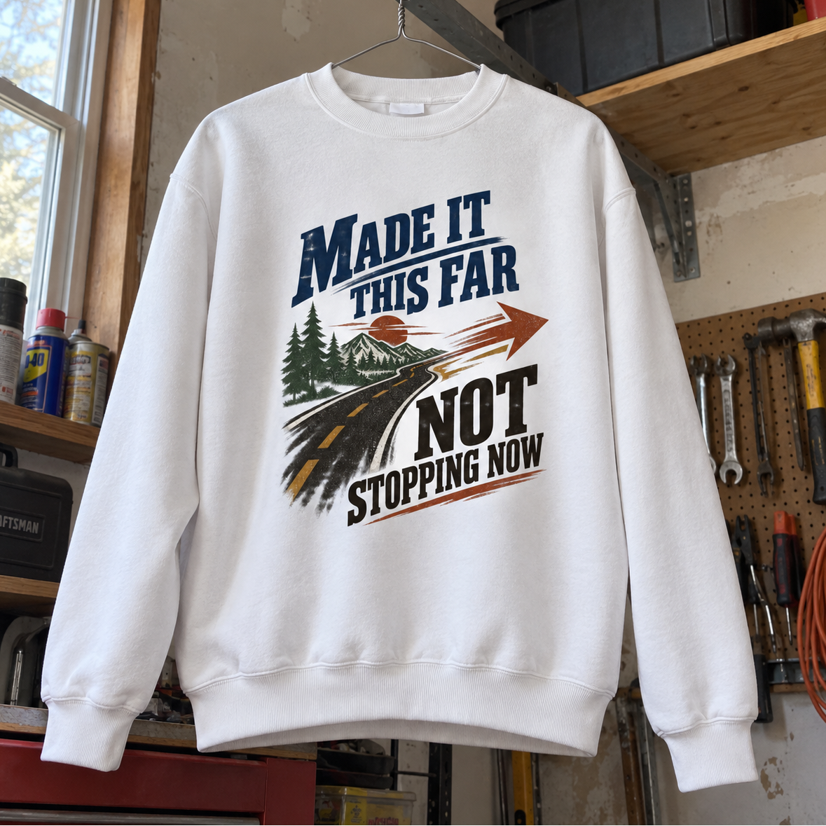 White vintage sweatshirt hanging in workshop, printed with Made It This Far Not Stopping Now