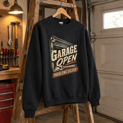 Black vintage sweatshirt with printed Garage Open Problems Solved design, hanging in a garage workshop