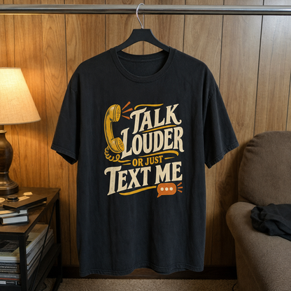 Vintage t-shirt hanging with printed “Talk Louder Or Just Text Me” slogan and telephone graphic.