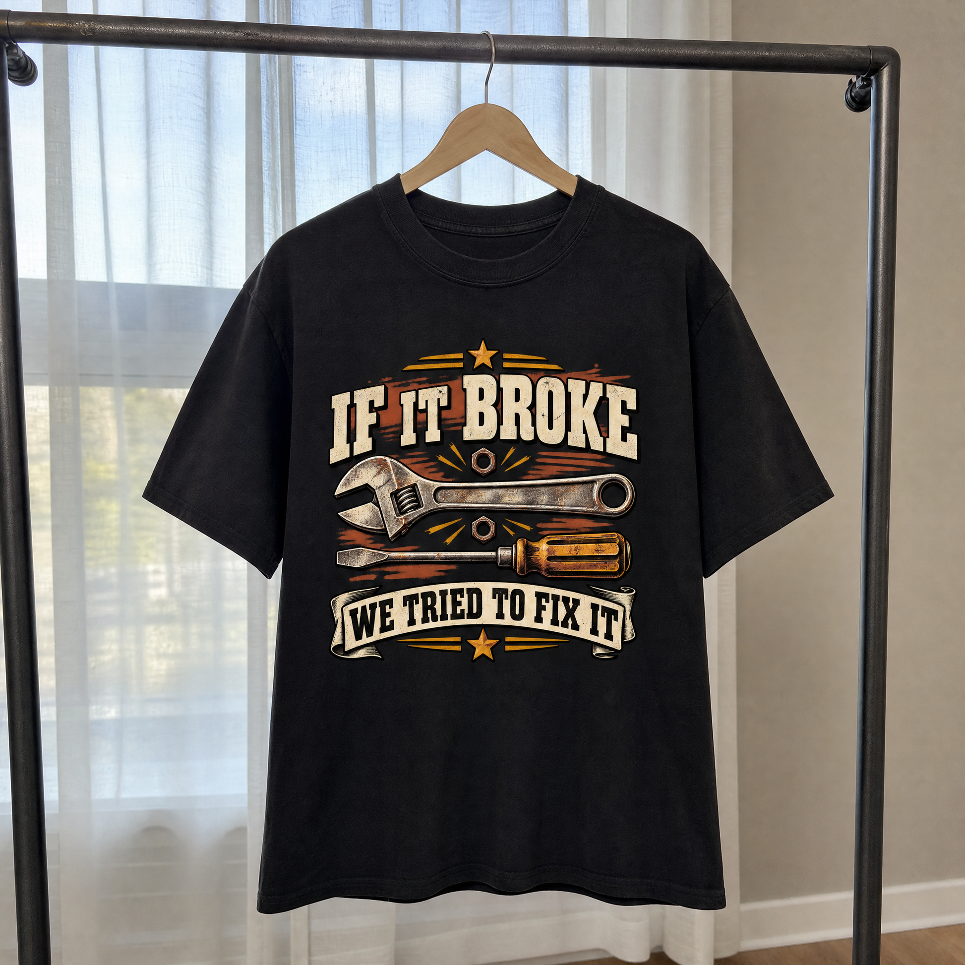 Black vintage t-shirt hanging with printed “If It Broke We Tried To Fix It”