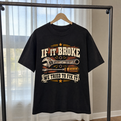 Black vintage t-shirt hanging with printed “If It Broke We Tried To Fix It”