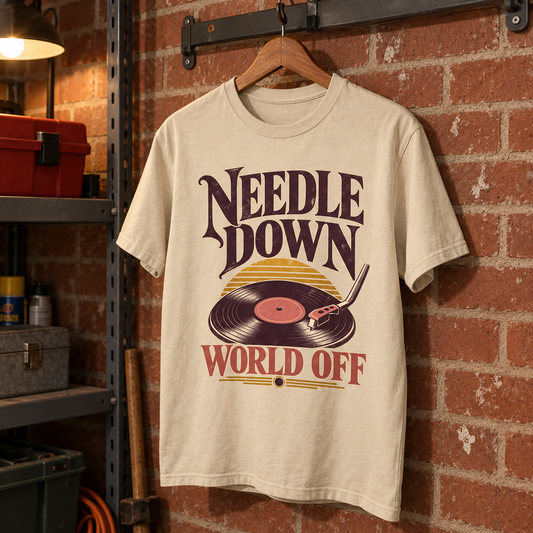 Cream vintage t-shirt hanging against brick wall, printed turntable and Needle Down World Off slogan