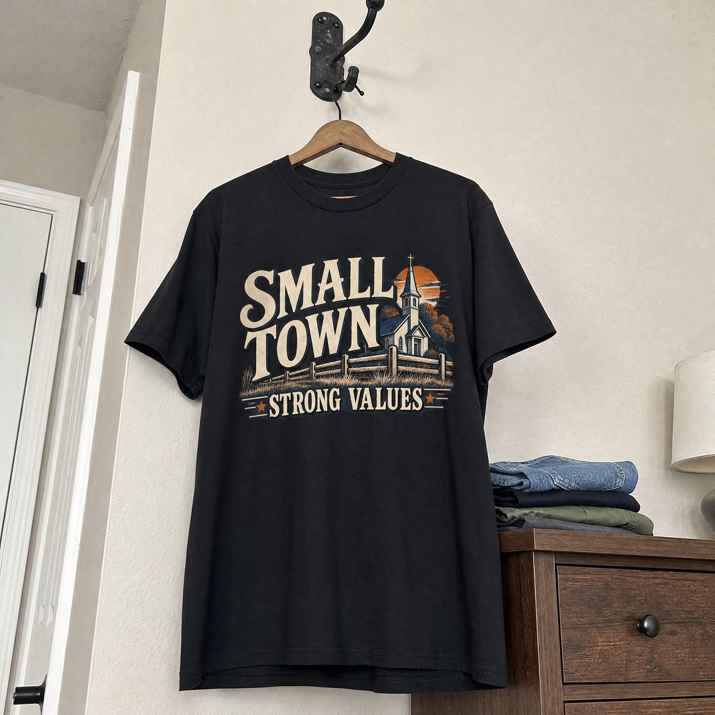 Black vintage t-shirt with printed Small Town Strong Values slogan hanging on wooden hanger