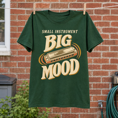 Green vintage t-shirt hanging with printed “Small Instrument. Big Mood” harmonica design.