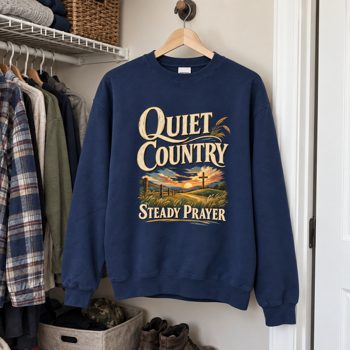 Navy vintage sweatshirt hanging in closet with printed Quiet Country Steady Prayer sunset design