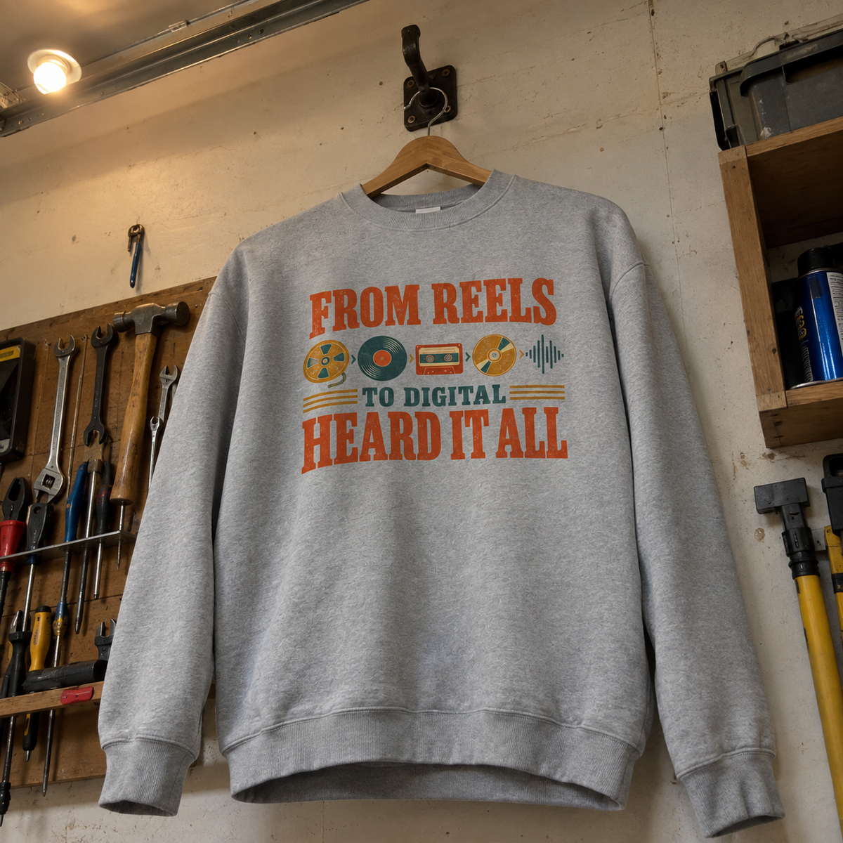 Gray vintage sweatshirt with printed From Reels To Digital Heard It All slogan hanging on wooden hanger