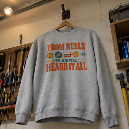 Gray vintage sweatshirt with printed From Reels To Digital Heard It All slogan hanging on wooden hanger