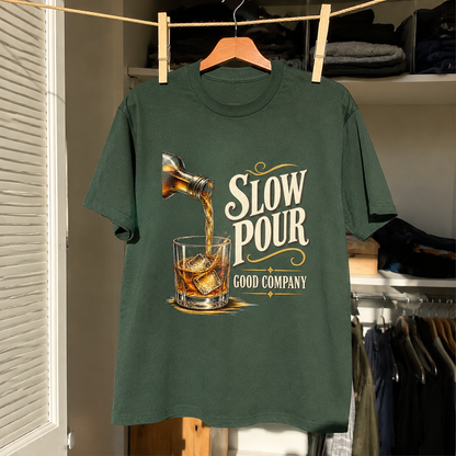 Green vintage t-shirt with printed Slow Pour Good Company design hanging on wooden hanger