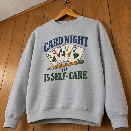 Gray vintage sweatshirt hanging with printed Card Night Is Self-Care design