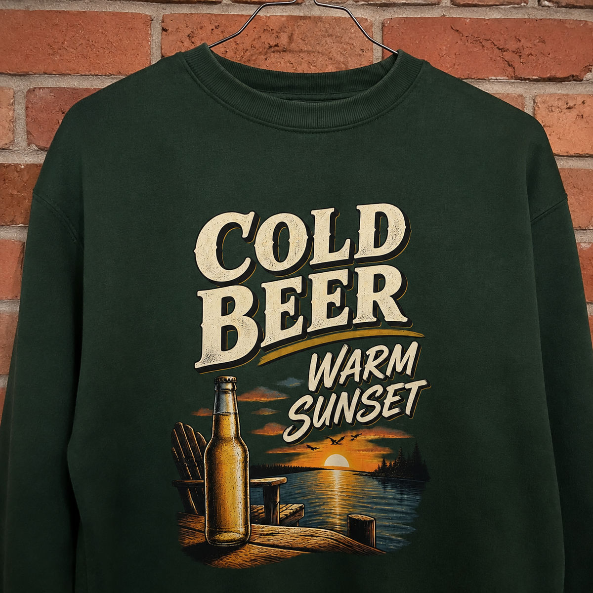 Hanging dark green vintage sweatshirt with Cold Beer Warm Sunset printed design and lake sunset