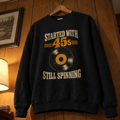 Black vintage sweatshirt with printed Started With 45s Still Spinning record design, hanging indoors