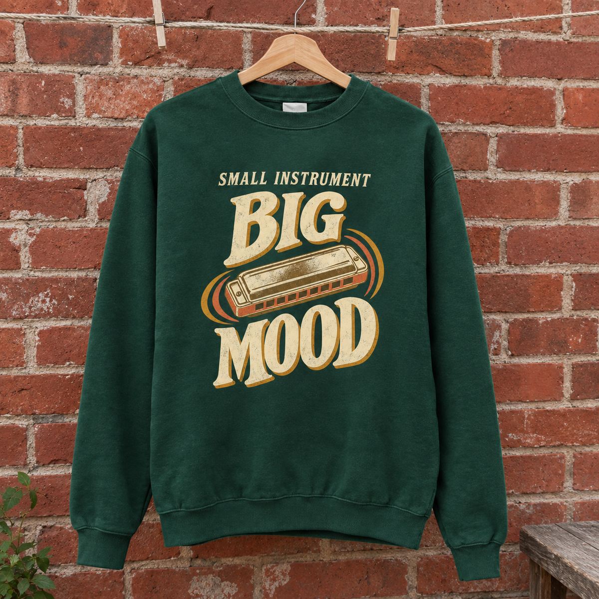 Green vintage sweatshirt hanging with Small Instrument Big Mood printed design, front view.