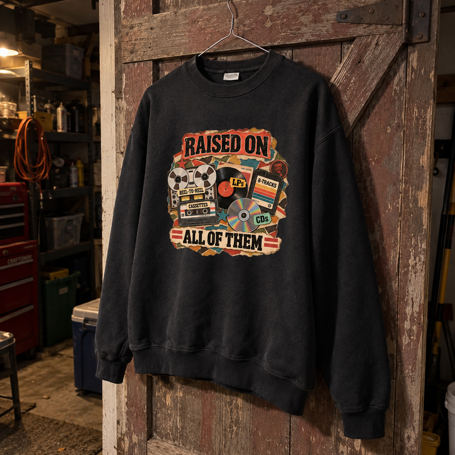Black vintage sweatshirt hanging on wooden door with printed Raised On All Of Them design