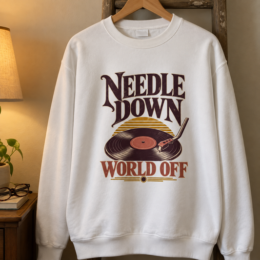 White vintage sweatshirt hanging on a wooden hanger with printed Needle Down World Off turntable design