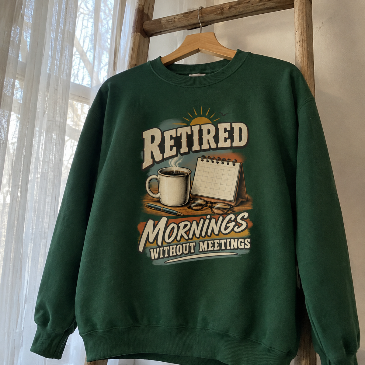 Green vintage sweatshirt hanging with printed Retired Mornings Without Meetings design